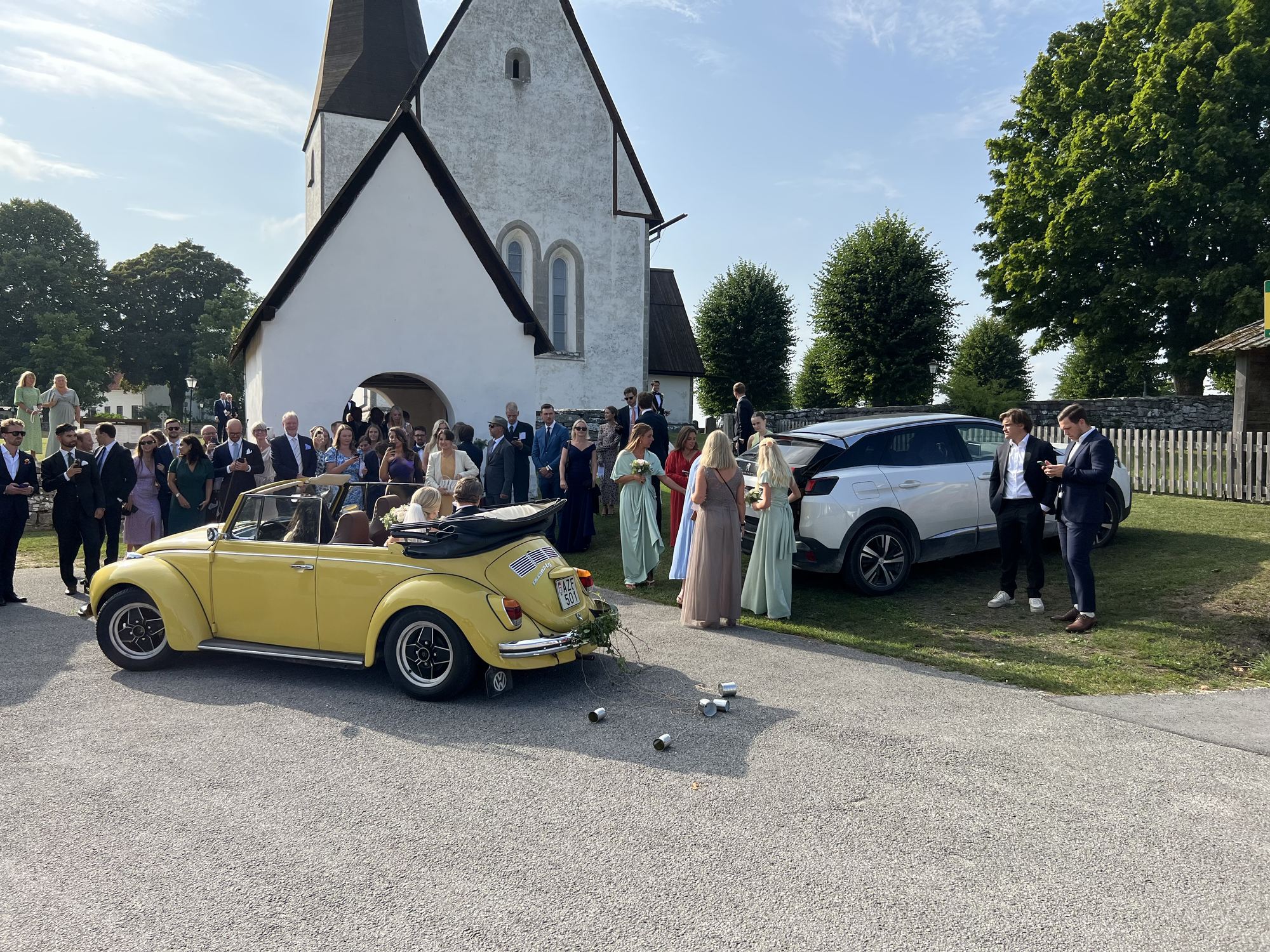 Brudparet lämnar kyrkan i en gul cabriolet